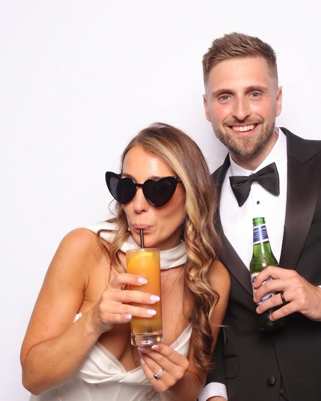 A bride and groom posing with props in the IkonikShots photo booth